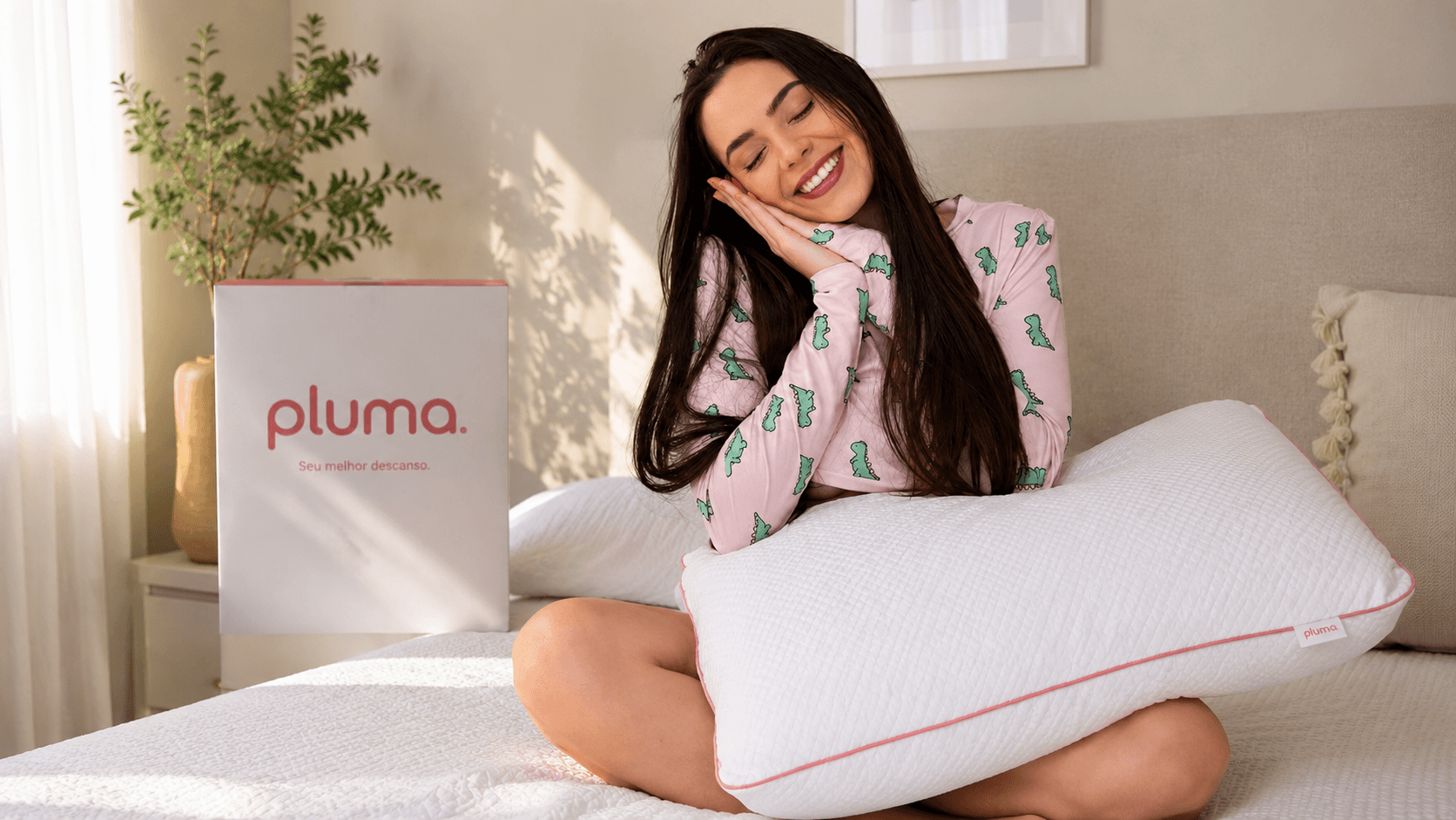 Influenciadora sentada na cama com o Travesseiro Antiestresse Pluma